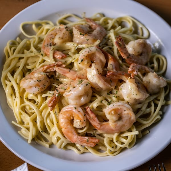 Creamy shrimp linguine pasta with herbs on a white plate at Juicy Claws Restaurant.