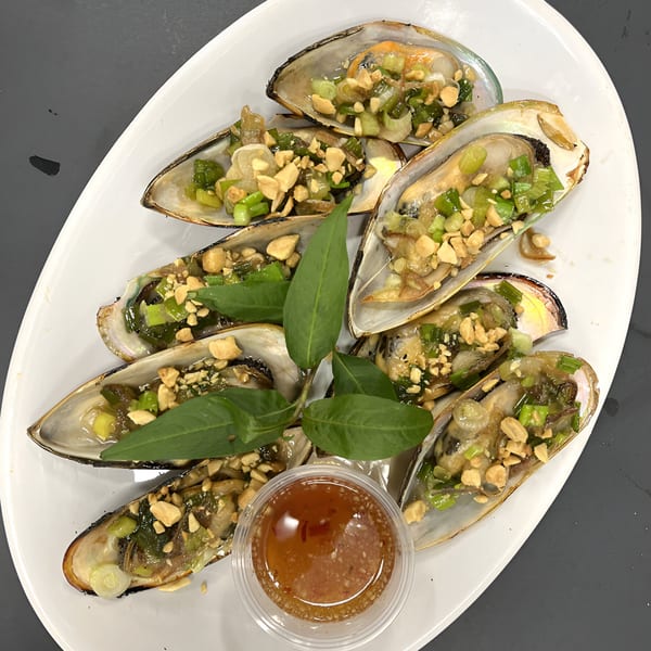 Juicy Claws' mussels topped with green onions, peanuts, and herbs, served with a dipping sauce.